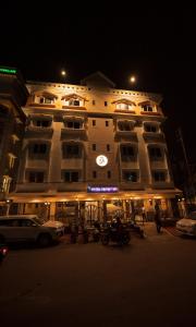 西里古里Rajdarbar Hotel & Banquet, Siliguri的一座大建筑,晚上有钟