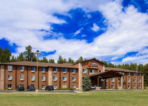 卡斯特Comfort Inn & Suites Near Custer State Park and Mt Rushmore的一座大型砖砌建筑,前面有汽车停放