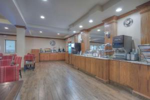 卡斯特Comfort Inn & Suites Near Custer State Park and Mt Rushmore的一间餐厅,在一间房间里设有酒吧,酒吧里摆放着红色的椅子