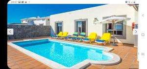 亚伊萨Villa Calma的房屋旁的游泳池配有椅子和遮阳伞