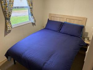 布莱克浦Blackpool Static Caravan Marton Mere的卧室内的一张蓝色的床,卧室设有窗户
