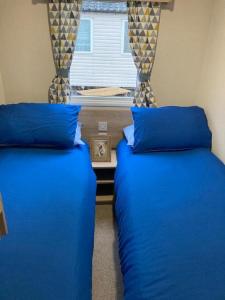 布莱克浦Blackpool Static Caravan Marton Mere的配有蓝色枕头和窗户的客房内的两张床
