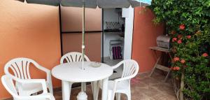 普拉亚多Karina Estudio的庭院里配有白色的桌椅和遮阳伞