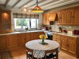 彭布罗克郡The Cottage的厨房配有木制橱柜和鲜花桌