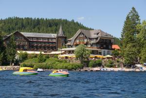 蒂蒂湖-新城Treschers Schwarzwald Hotel的两艘船在度假村前的水中
