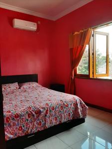 日惹拉巴尼家庭度假屋的一间卧室设有一张红色墙壁和窗户的床