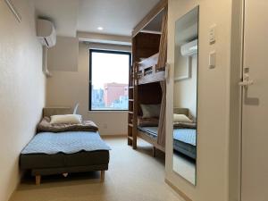 东京Tokyo Ueno Youth Hostel的小房间设有双层床和窗户