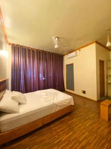 弗里德胡Bougainvillea Inn - Maldives的一间卧室配有一张床和紫色窗帘