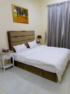 阿吉曼Al Rawda Apartments -Ajman的一间卧室配有一张带白色床单的大床
