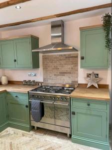 金斯林Ferry Lane Cottage的厨房配有绿色橱柜和炉灶。
