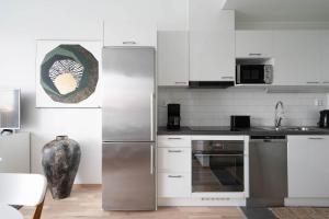 赫尔辛基Premier Residences Helsinki的厨房配有白色橱柜和不锈钢冰箱