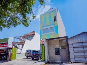 泗水Super OYO Capital O 90336 Olive Guest House的一座多彩的建筑,汽车停在停车场