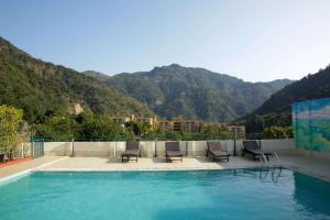 瑞诗凯诗Hotel Dewa Retreat- A Himalayan Boutique Hotel的一个带椅子的游泳池,背景是山脉