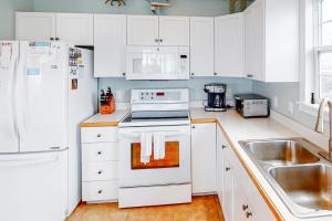 哈特勒斯3 Little Birds #14-H的厨房配有白色橱柜和白色炉灶烤箱。