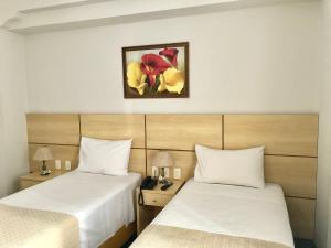 里约热内卢OK酒店的酒店客房设有两张床,墙上挂着一张照片。