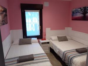 伊巴兰格鲁Playa Laga的配有粉红色墙壁和窗户的客房内的两张床