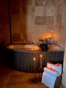 乌奇希萨尔Alice in Cappadocia的浴室配有带蜡烛和毛巾的浴缸。