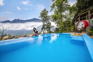 萨帕图博特尔沙巴旅馆的坐在游泳池边缘的一位女性,游泳池的背景是山地