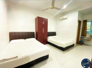 斯里曼绒Motel Fasa2B的一间卧室配有两张床和橱柜