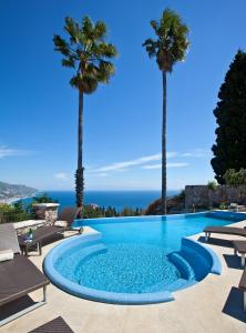 陶尔米纳阿什比酒店的棕榈树和大海的游泳池