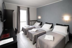 奥尔巴萨诺J酒店的酒店客房设有三张床和电视。