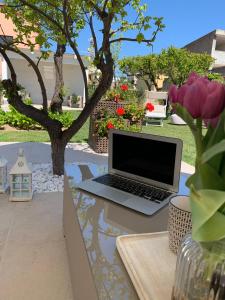 奥尔比亚Enjoy Your Stay - Guest House - Olbia的坐在花园里桌子上的笔记本电脑