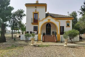 塞维利亚Cortijo San José的黄色和白色的小房子,设有门廊