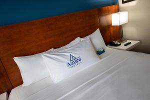 梅萨The Azure Hotel的一张带白色枕头的床,上面有黑线标志