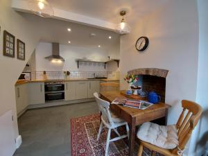 韦尔斯St Etheldreda's Cottage, Wells, Somerset的厨房配有木桌和壁炉。