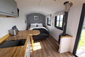 约克Springwood Shepherd Huts Glamping York的一间厨房和客厅,客厅里设有一张床,位于一个小房子里