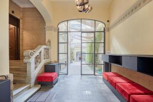 巴塞罗那Le Palacete powered by Sonder的通往带红色沙发和楼梯的大楼的入口