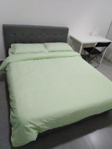 塞贝维Mayzi Holiday Home @ Cyberjaya的一张带绿色棉被和一张桌子的床