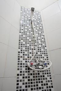 巨港特里克拉典范旅馆的黑色和白色瓷砖地板上带软管的淋浴