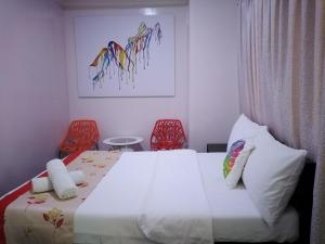 麦克坦HalfWay House Hostel Mactan Cebu Airport的一间卧室配有一张床和两张红色椅子