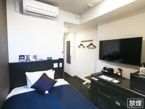 横滨HOTEL LiVEMAX Yokohama Stadium Mae的配有一张床和一台平面电视的酒店客房