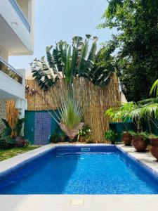 科托努L'Oasis Guesthouse的棕榈树庭院中的游泳池