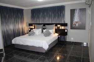 比勒陀利亚格兰查帕拉尔旅馆的卧室配有一张带白色床单和枕头的大床。