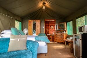 雷因恩道尔Fernhill Tented Treehouses的一间卧室配有一张床,一张沙发位于帐篷内