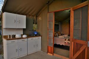 ChobeMuchenje self-catering Tents的一间厨房,配有白色的橱柜和一张帐篷内的床铺