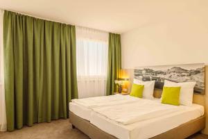黑尔博尔茨海姆海威高速公路酒店的一间卧室配有一张带绿色窗帘的大床