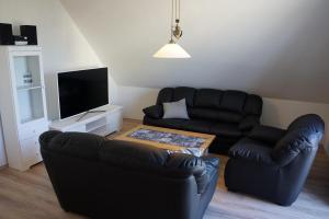 Groß KirrHaegerende 52 OG _Kapitaenshaus_的客厅配有黑色真皮沙发和电视