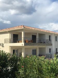 阿莱里亚Mare e Monti的大型白色房屋,阳台上配有椅子
