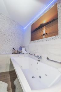 托雷洪-德阿尔多斯Hostal La Carretera的浴室设有白色浴缸,墙上配有电视。