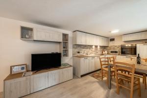 维哥迪法萨Appartamento Ciasa Ciaslir的厨房配有白色橱柜和一张桌子及一台电视机