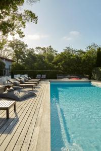 梅桑热Hotel La Maison de la Prade的一个带躺椅和木甲板的游泳池