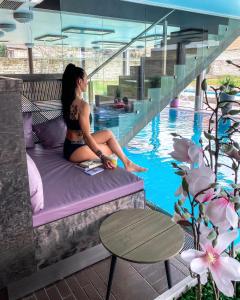 库雷萨雷乔安设计水疗酒店的坐在游泳池旁床边的女人
