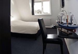 艾默伊登皇家酒店的一间卧室配有一张床和一张椅子,桌子上配有一张小船