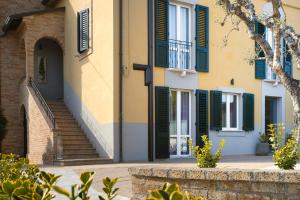 西维尔诺瓦·马尔凯La Locanda dei Cavalieri Country House的一座带绿色百叶窗和楼梯的建筑