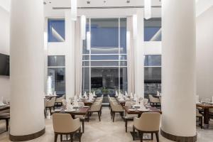 吉达Qamar Hotel Jeddah的餐厅设有白色的圆柱和桌椅