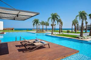 赫尔格达Rixos Premium Magawish Suites and Villas- Ultra All-Inclusive的木制甲板上的带野餐桌的游泳池